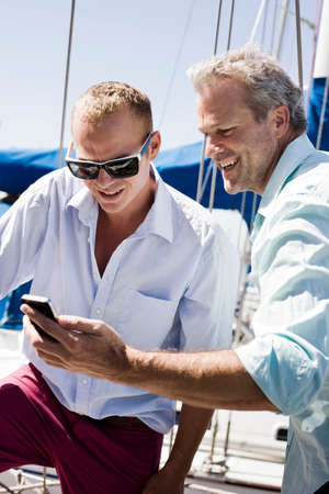 Two men on yacht with smartphoneの写真素材