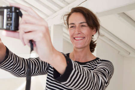 Woman photographing self with digital camera