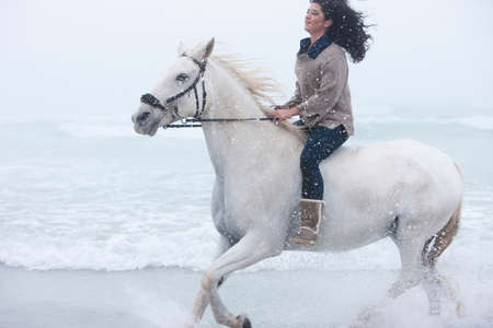 Woman riding horse on beach