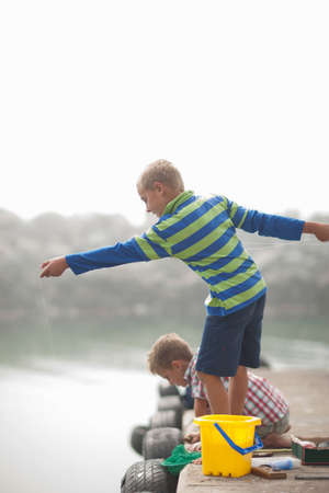 Two young boys fishing on pierの写真素材