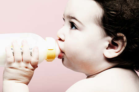Portrait of baby girl drinking milk from bottleの写真素材
