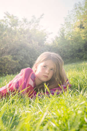 Girl lying down in field during summerの写真素材