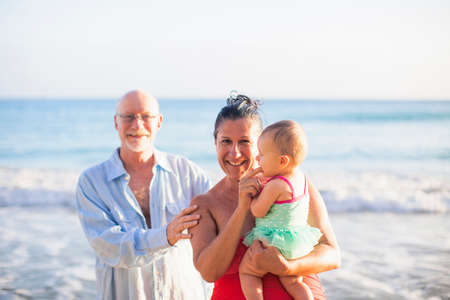 Grandparents holding granddaughter by sea, St Maarten, Netherlandsの写真素材