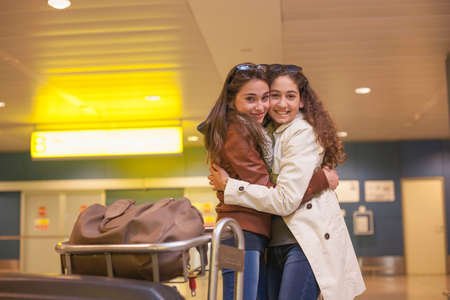 Two teenage girls hugging in airport