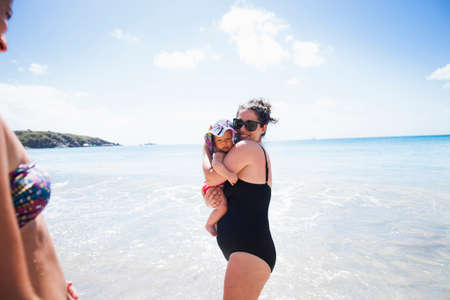 Mother holding baby daughter in sea, St Maarten, Netherlandsの写真素材