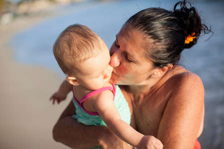 Grandmother kissing baby granddaughter on cheekの写真素材