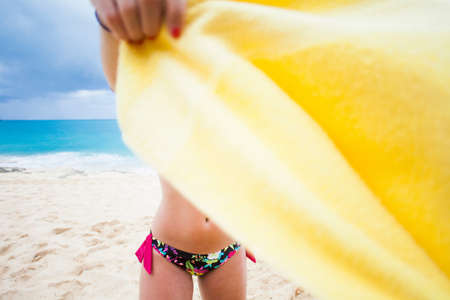 Woman holding yellow towel on beach, St Maarten, Netherlandsの写真素材