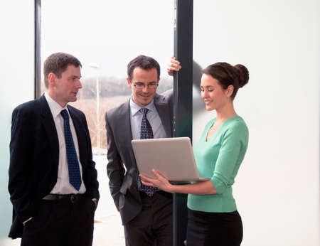 Three colleagues talking, woman holding laptopの写真素材