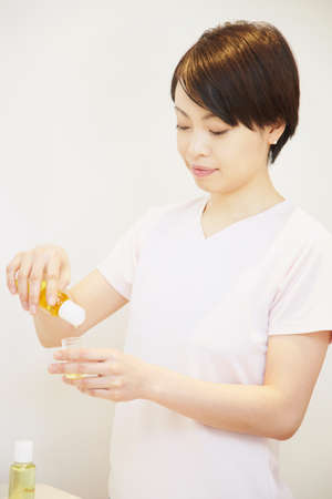 Woman pouring aromatherapy oil into containerの写真素材