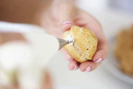 Woman filling profiterole with creamの写真素材
