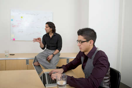 Young men at work, one man using laptop
