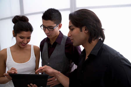 Three young businesspeople using digital tablet
