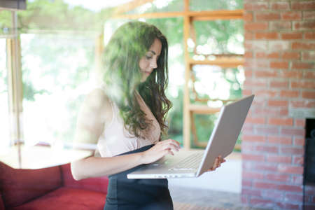 Woman using laptop in living roomの写真素材