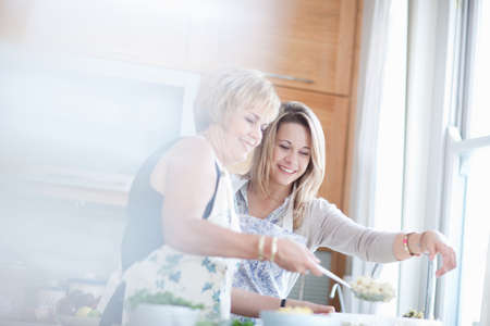 Mother and daughter cooking in kitchenの写真素材