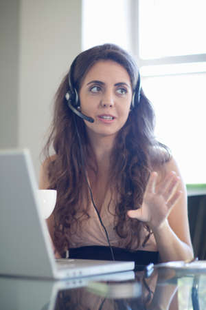 Businesswoman wearing headset at desk
