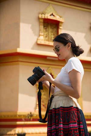 Woman holding camera outside buildingの写真素材