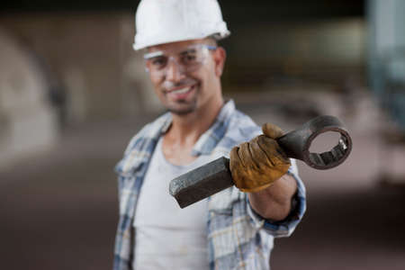 Mid adult construction worker wearing hard hat and holding wrench, portraitの写真素材