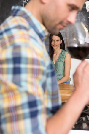 Mid adult man smelling glass of wine, woman in foregroundの写真素材