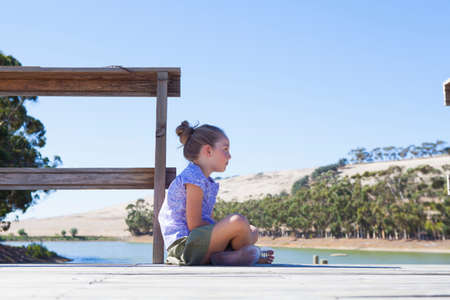 Girl sitting on pier, side viewの写真素材