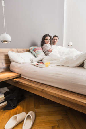 Mid adult couple lying in bed, breakfast on tray