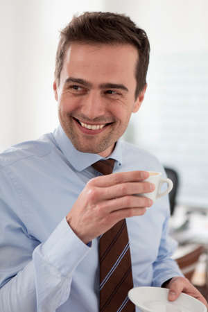 Mature man wearing shirt and tie holding cup of coffeeの写真素材