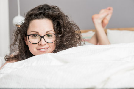 Mid adult woman lying on front on bedの写真素材