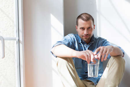 Mid adult man sitting holding drinking glass