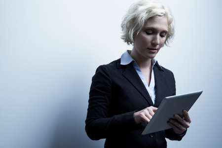 Studio portrait of blond businesswoman with digital tabletの写真素材