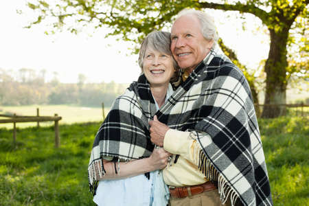 Senior couple wrapped in shawl togetherの写真素材