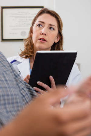 Mid adult doctor using digital tablet and listening to patientの写真素材