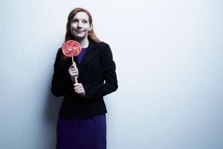 Studio portrait of young businesswoman holding red lollipopの写真素材