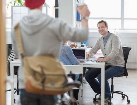 Young man arriving at meeting in creative office