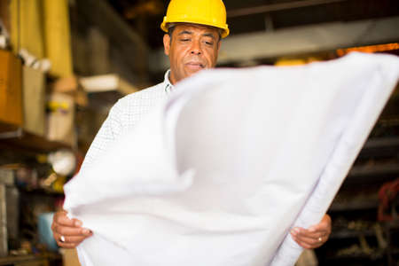 Man in warehouse holding up blueprint