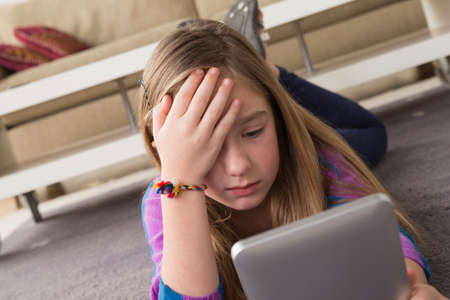 Girl looking at digital tablet in puzzlement