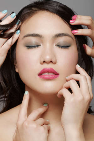 Close up of woman's face surrounded by hands