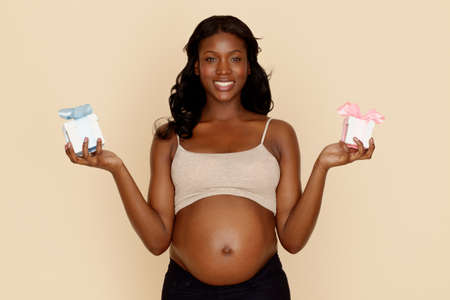 Pregnant young woman holding blue and pink gift boxesの写真素材