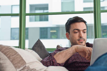 Young man at home using digital tabletの写真素材