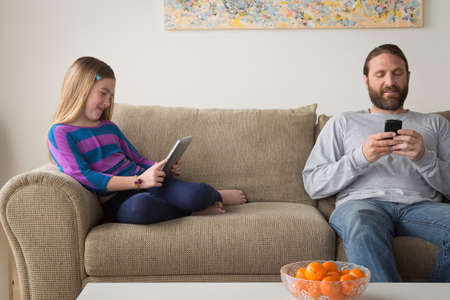 Father and daughter sitting on couchの写真素材