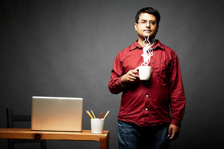 Man holding cup of steaming hot beverage