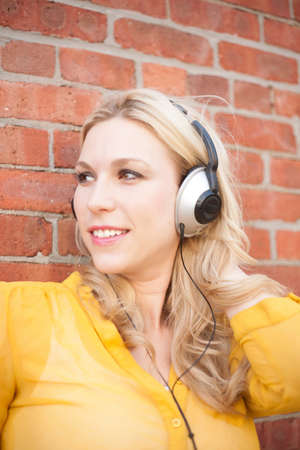 Close up of woman with headphones against brickwallの写真素材