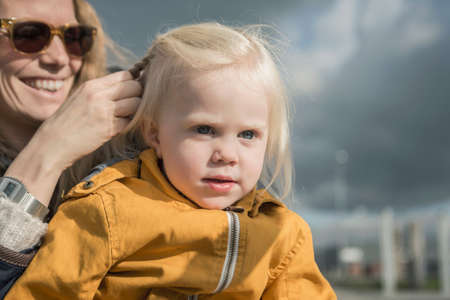 Outdoor portrait of mother braiding toddlers hair