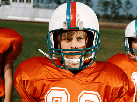Boy wearing American football helmet, looking awayの写真素材