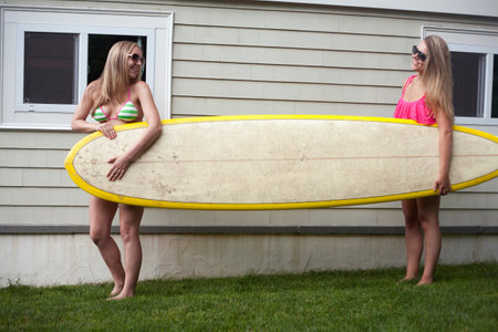 Young women carrying surfboard on grassの写真素材
