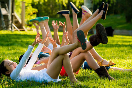 Girls lying on grass with arms and legs raisedの写真素材