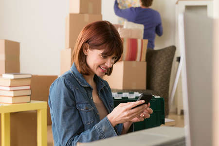 Woman looking at cellphone whilst moving house