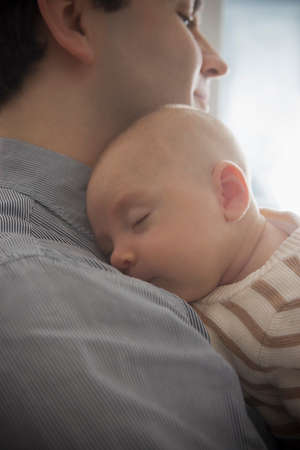 Baby boy sleeping on father's shoulder, close upの写真素材