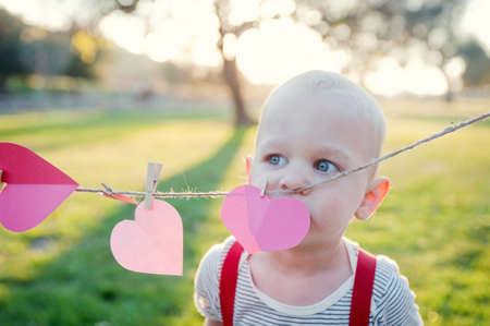 Young boy looking over heart shapes on washing lineの写真素材