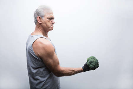 Senior man in sports clothing lifting broccoliの写真素材