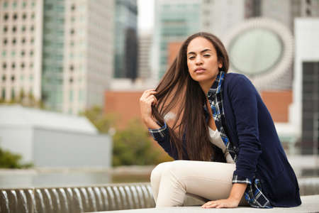 Young woman sitting in city, portraitの写真素材