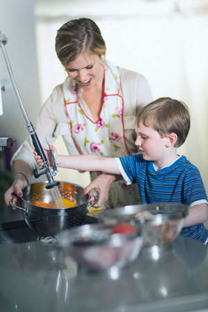 Mother and son washing vegetables in sink at homeの写真素材